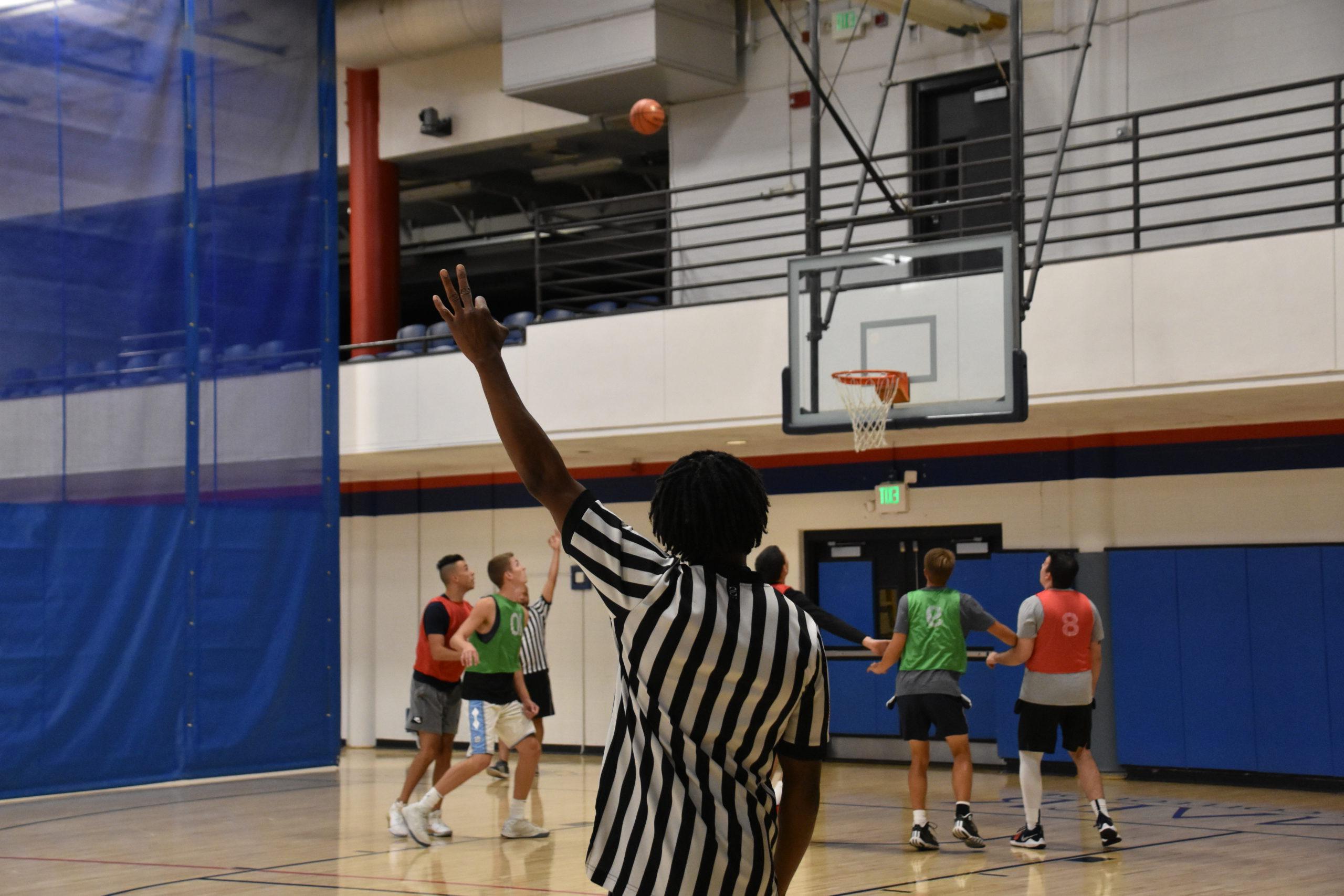 Intramural basketball official showing a 3 point attempt